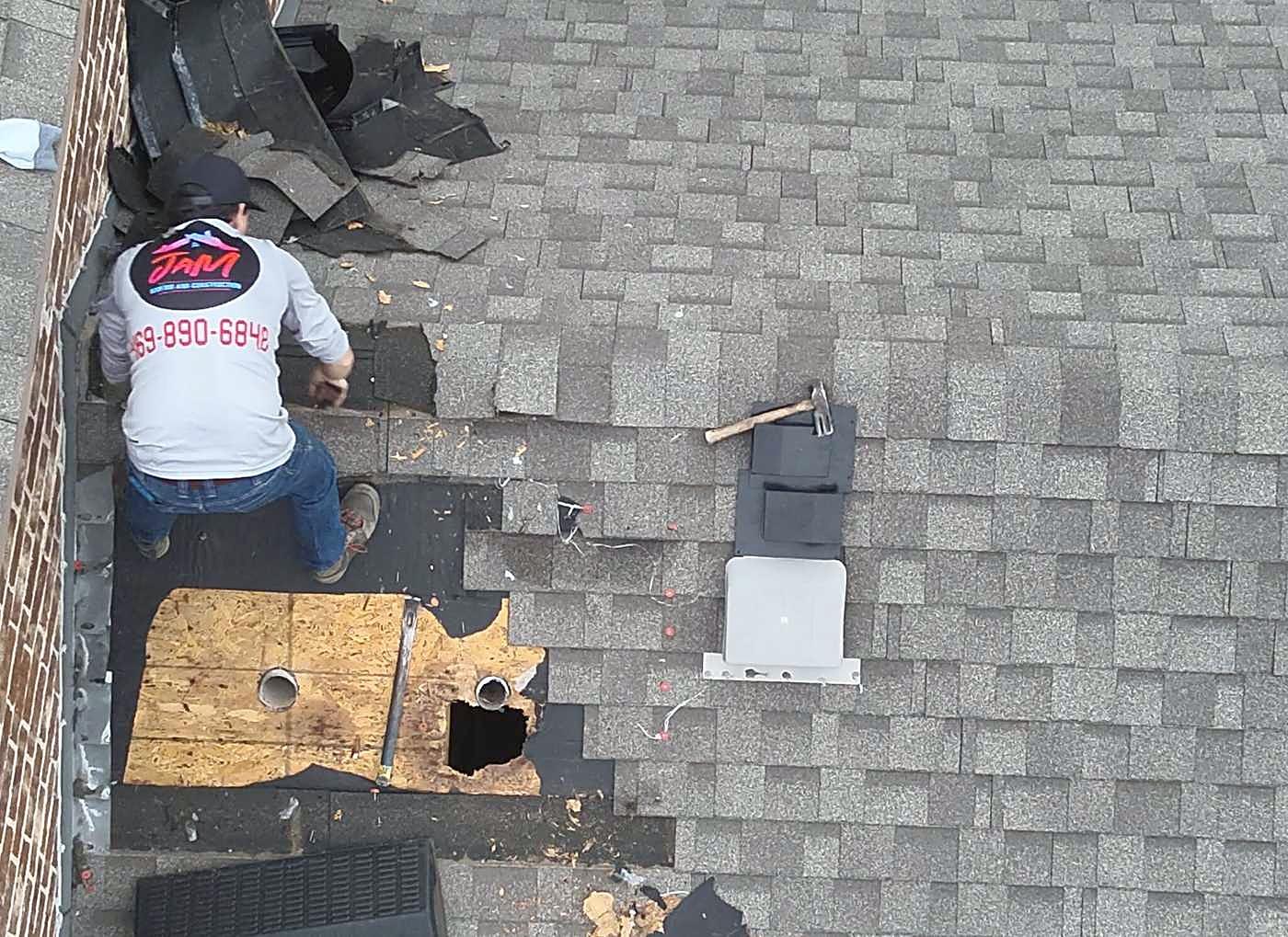 A roofer in a JaM Roofing shirt working on an opened section of roof decking