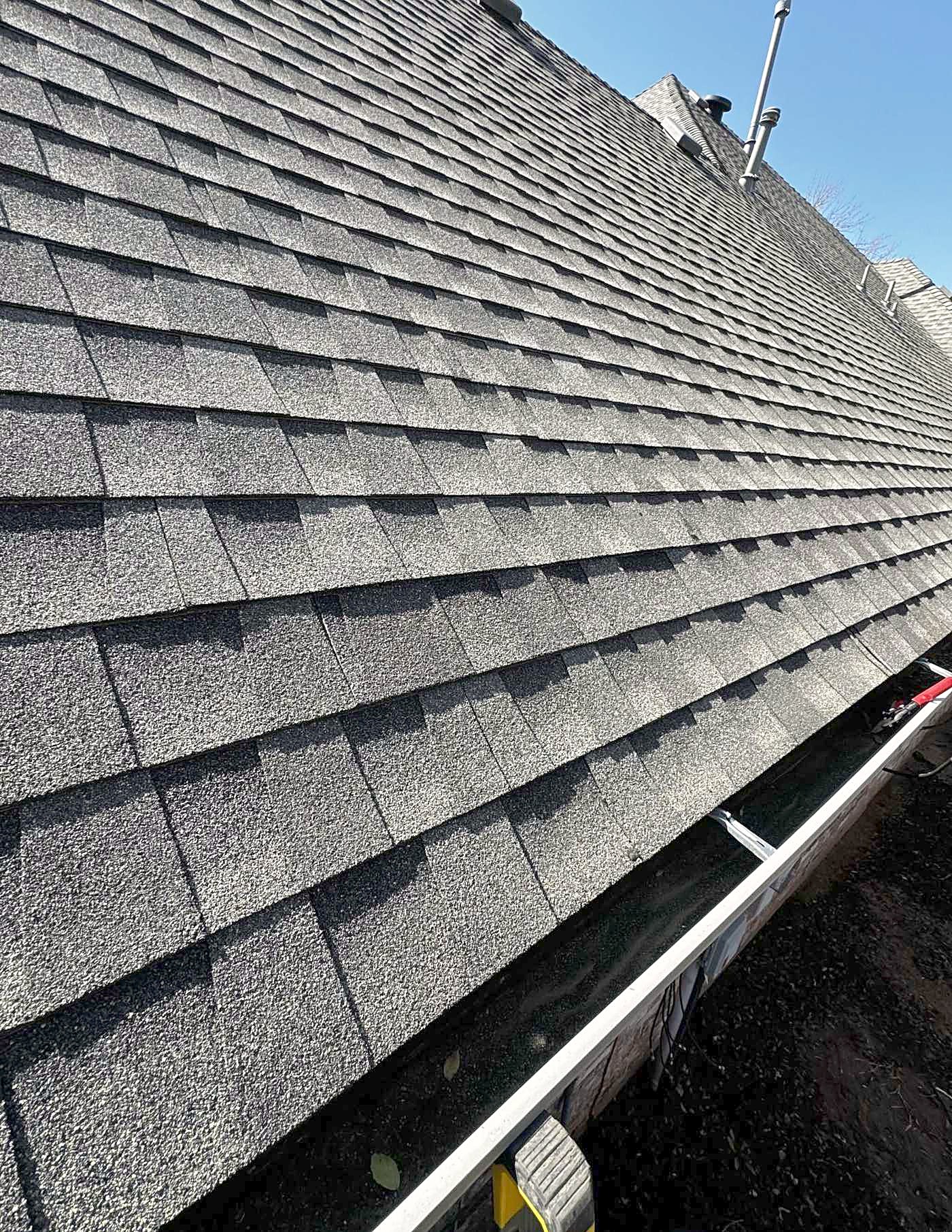 A close view of a shingle roof running down to the gutter line